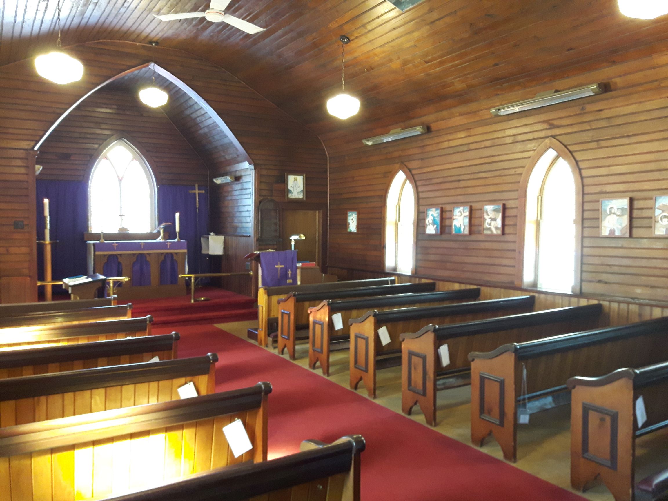 Interior view of the small chapel featuring wodden benches and the pulpit.